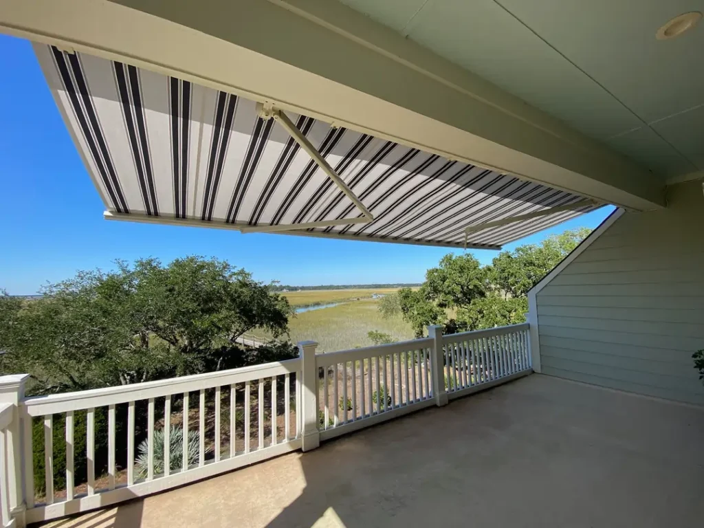 Under the shade of a SunSetter awning in white with navy stripes.